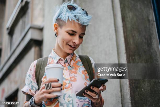 woman holding phone and coffee to go - tattoo woman stock pictures, royalty-free photos & images