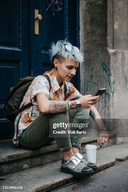 frau hält telefon und kaffee zu gehen - coiffure punk stock-fotos und bilder