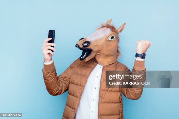 euphoric horse man with raised fists and smart phone in hand - smartphones dangling stock pictures, royalty-free photos & images