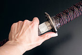 Samurai sword and scabbard in hand on wooden background