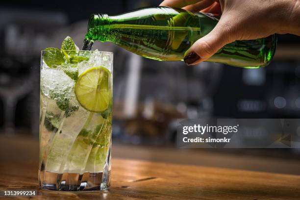 nahaufnahme von strömendem sekt in cocktail - softdrinks bottle stock-fotos und bilder