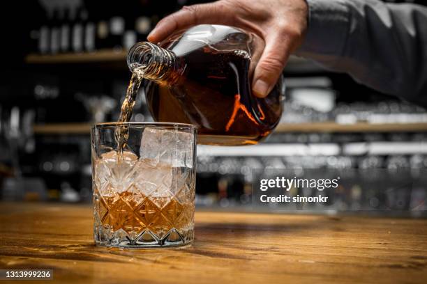 de hand die van de mens whisky in glas giet - whisky stockfoto's en -beelden