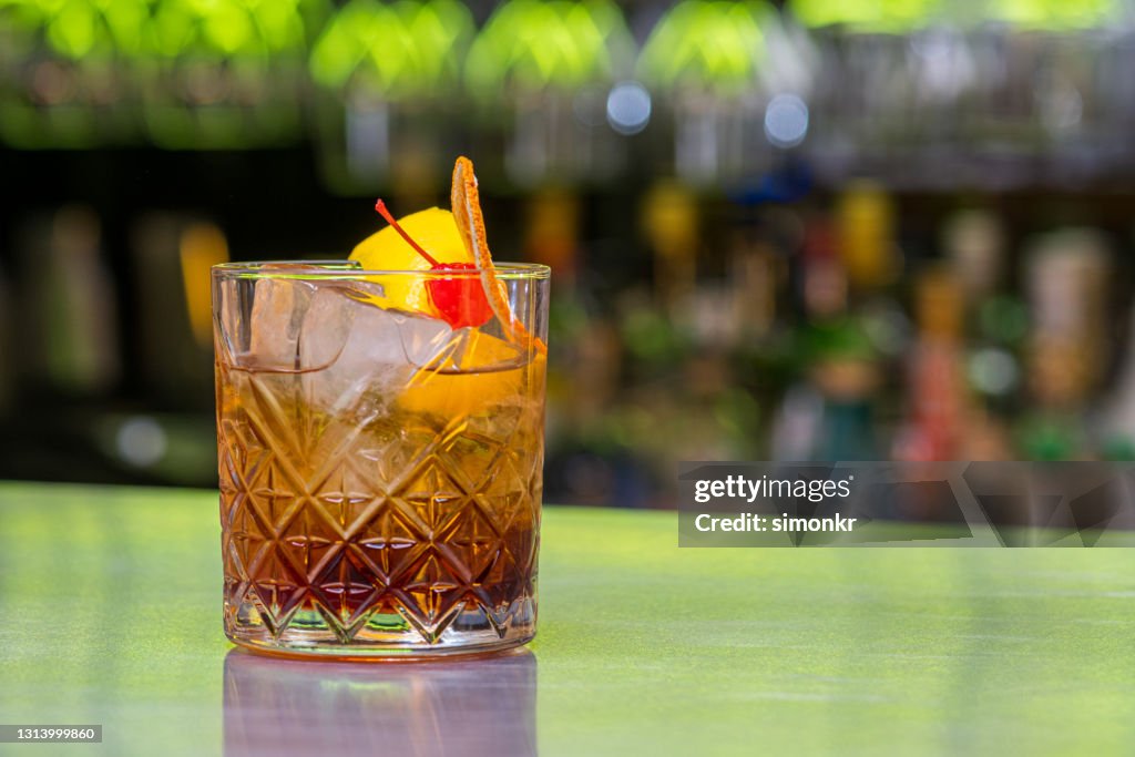 Glass of rum with ice cubes, cherry and orange slice