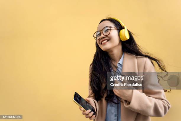 young asian woman with headphones - headphones woman stock-fotos und bilder