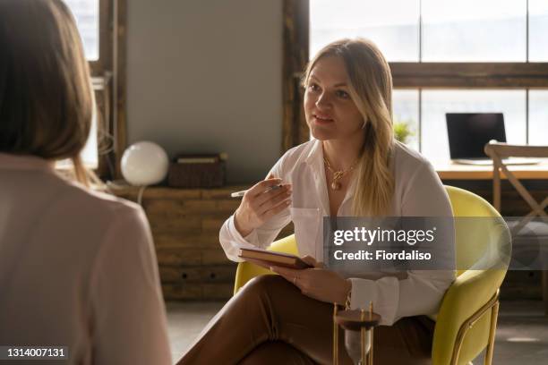 woman psychologist talking to patient - psychiatry stock-fotos und bilder