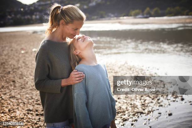 mother with duaghter standing at a riverbank - love on the rocks stock pictures, royalty-free photos & images