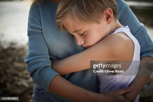 mother and son hugging outdoors - triste imagens e fotografias de stock
