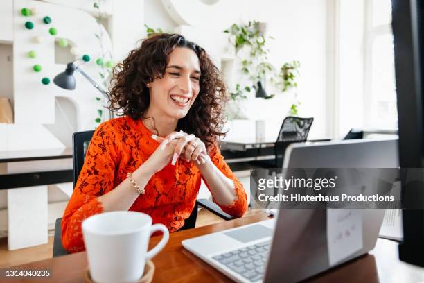 transgender woman smiling while video calling business partner - woman business desk front laptop office bildbanksfoton och bilder