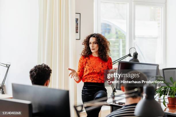 transgender office manager addressing group of people during meeting - germany team presentation stockfoto's en -beelden