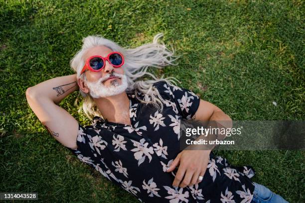 rijpe mens die op gras ligt - lying down stockfoto's en -beelden