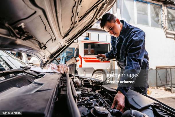 mechanic examining car diagnostics on digital tablet - auto mechanic shop stock pictures, royalty-free photos & images