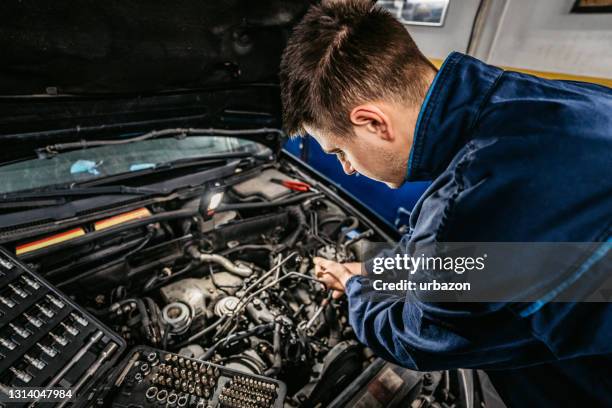 mecánico de automóviles trabajando en un coche en su garaje - filtración fotografías e imágenes de stock