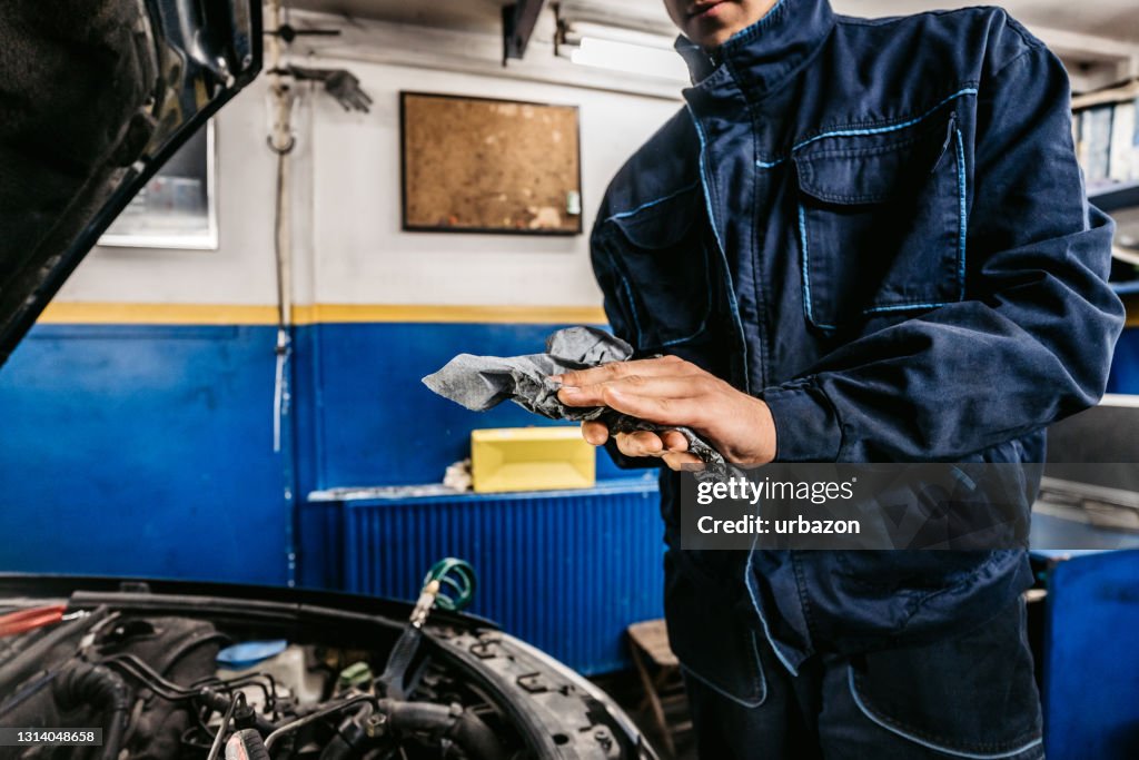 Auto mechanic cleaning hands after working on car engine in a garage