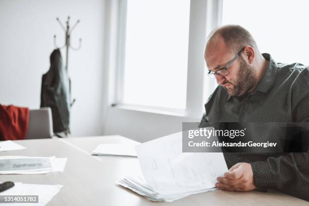 male ceo reviewing papers in office - balding fat man with glasses stock pictures, royalty-free photos & images