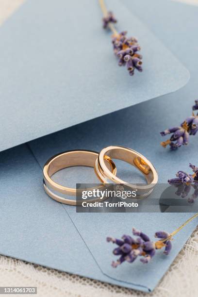 pair of modern gold wedding rings in on blue invitation envelope - alta moda fotografías e imágenes de stock