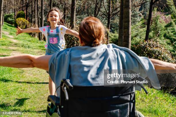 cute girl running to hug her grandmother sitting in a wheelchair - mother daughter hospital running stock pictures, royalty-free photos & images