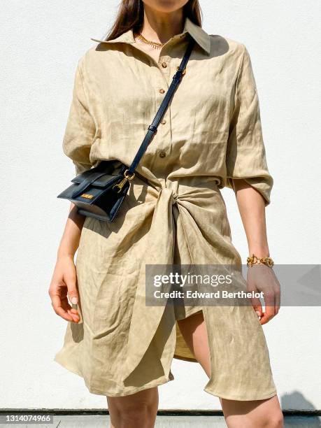 Julia Comil wears a beige button-down midi wrap beach dress in linen in beige by Anemos, a top handle cross body small black leather bag: Le bambino...