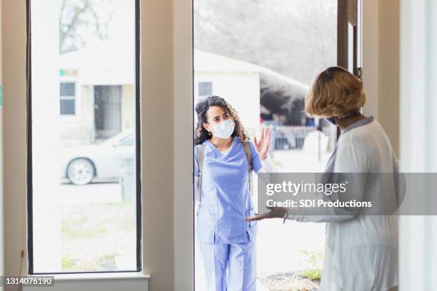 de hogere vrouw verwelkomt de verpleegster van de huisgezondheidszorg in haar huis - house call stockfoto's en -beelden