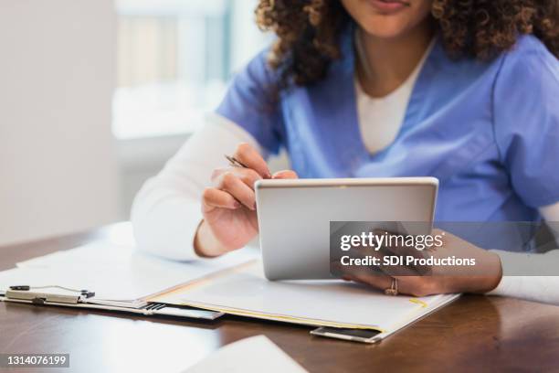 krankenschwester verwendet digitales tablet während hausbesuch - krankenblatt stock-fotos und bilder