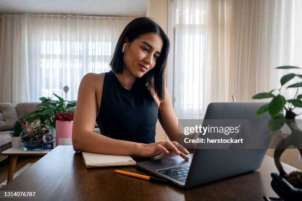 jovem tendo chamada de vídeo com laptop em casa. - video conference - fotografias e filmes do acervo