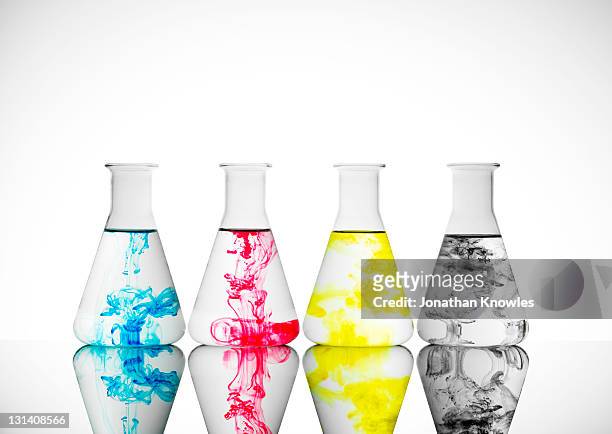 four lab glass bottles with ink in cmyk colors - cmyk foto e immagini stock