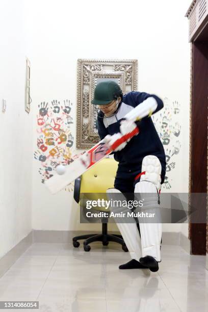 a young boy playing cricket (sport) and hitting a ball with bat inside the home. - cricket player white background stock-fotos und bilder