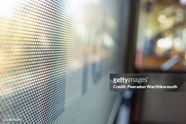 selective focus, close-up view at one way vision sticker film with dot pattern on glass of train's window and blurry background of train's passenger train and bokeh. - one way stock pictures, royalty-free photos & images