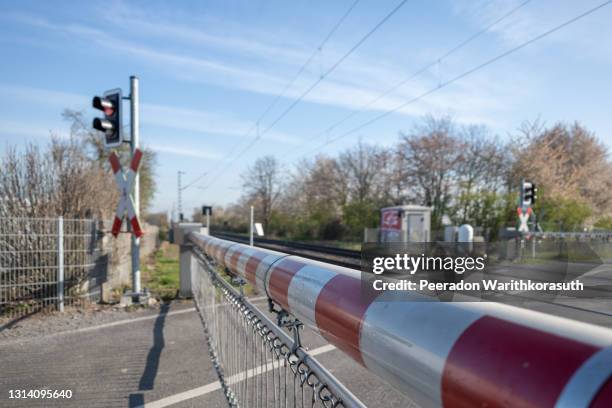 outdoor sunny and selective focus view at red and white level crossing railway barrier block a road on countryside in germany. - construction barrier stock-fotos und bilder