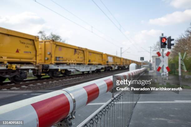 ed and white level crossing railway barrier which block the road and freight train. - barreira de construção - fotografias e filmes do acervo