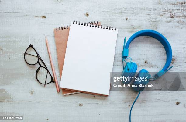 eyeglasses, note pad with copy space for text and earphones on gray wooden background, education and creativity concept. - notepad white table foto e immagini stock