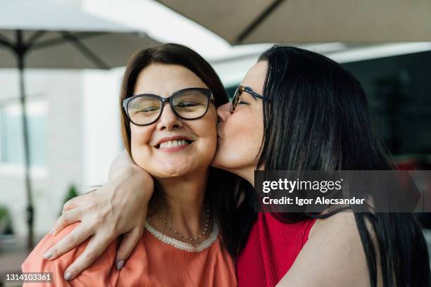 daughter kissing and hugging her mother - mother and daughter kissing stock pictures, royalty-free photos & images