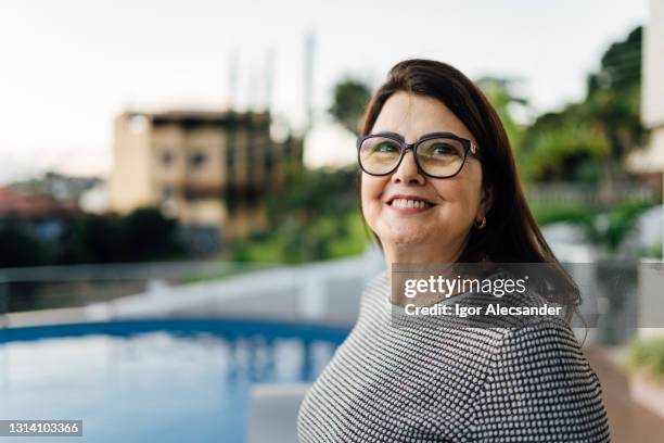 reife frau blickend zur seite vor einem schwimmbad - portrait spontaneous stock-fotos und bilder