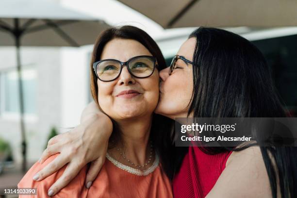 tochter küsst und umarmt ihre mutter - mother and daughter kiss happy stock-fotos und bilder