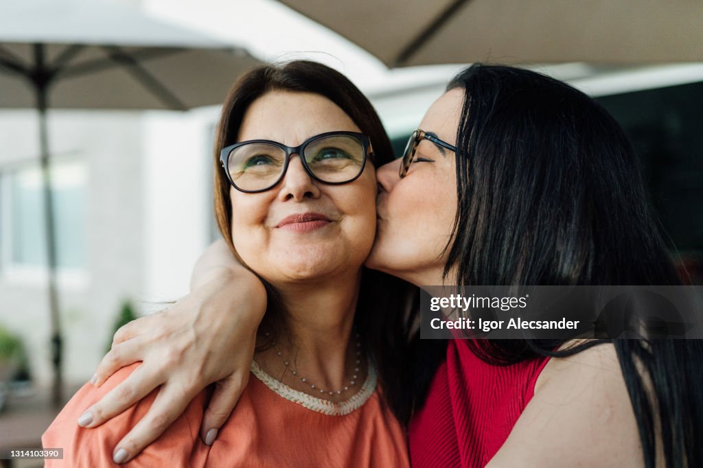 Filha beijando e abraçando sua mãe