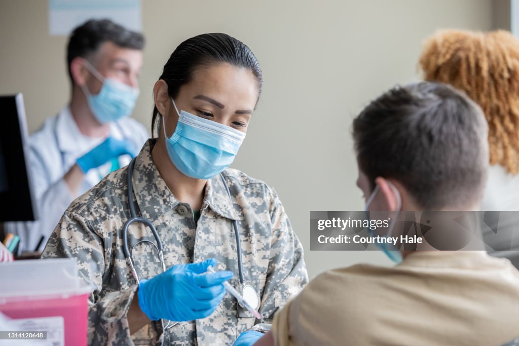 Mature soldier is military doctor giving COVID-19 vaccine injections