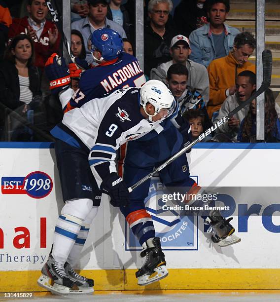 Evander Kane of the Winnipeg Jets hits Andrew MacDonald of the New York Islanders at the Nassau Veterans Memorial Coliseum on November 3, 2011 in...