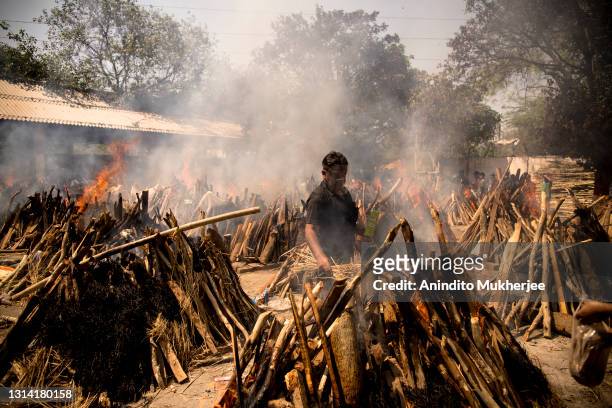 Man performs the last rites of his relative who died of the Covid-19 coronavirus disease as other funeral pyres are seen burning during a mass...