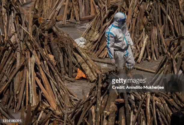 Man wearing PPE kit can be seen amid funeral pyres before they were lit to perform the last rites of the patients who died of the Coronavirus disease...