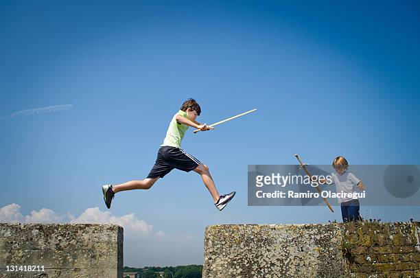 boys playing on castle with swords. jumping a wall - castle in uk stock pictures, royalty-free photos & images