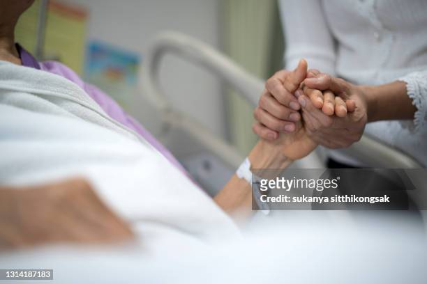 shot of daughter encourage her mother and holding the mother's hand to sleep on the bed ​in hospital. - cancer illness stock pictures, royalty-free photos & images