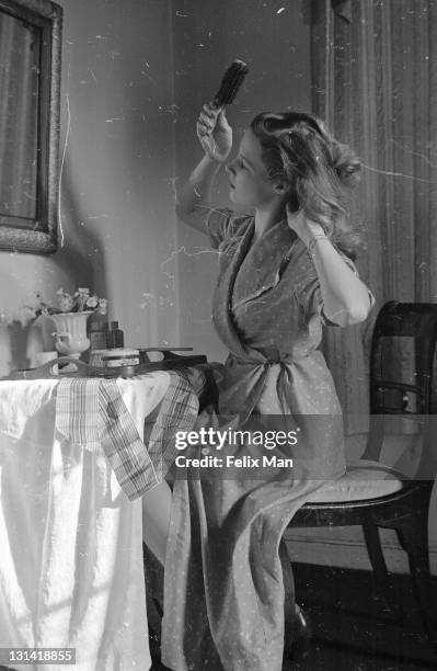 Woman brushing her hair at a makeshift dressing-table in the home she and her husband have furnished in wartime, 3rd April 1943. Original Publication...