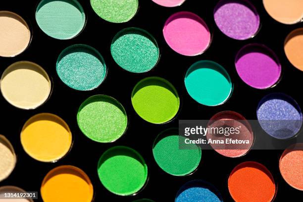 set of many multicolored eyeshadows in black palette for bright look. concept of holiday and carnival make-up of rainbow and nude colors with shimmer: red, orange, yellow, green, light blue, purple and beige. extreme close-up and flat lay style - eyeshadow foto e immagini stock