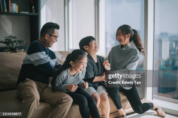 asian chinese 2 parent tickling playing with their children at home in living room cuddle on sofa - mother daughter couch imagens e fotografias de stock