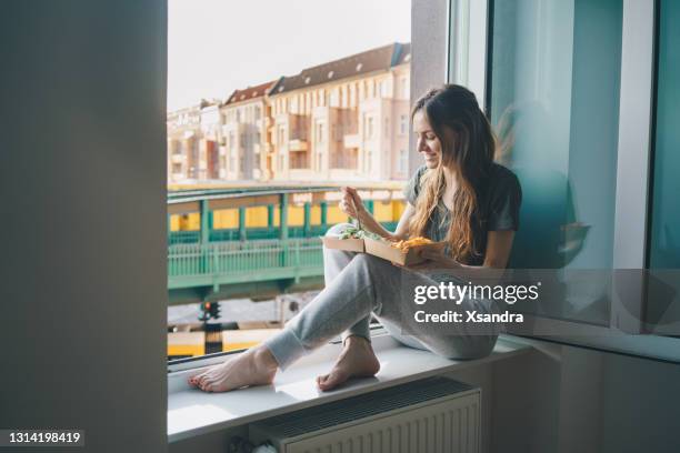 vrouw met neem salade thuis op de vensterbank - berlin lifestyle stockfoto's en -beelden