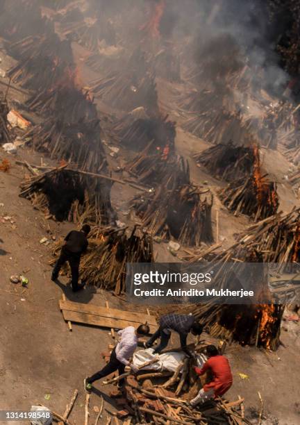 People perform the last rites of a relative who died of the Covid-19 coronavirus disease as other funeral pyres are seen burning during a mass...