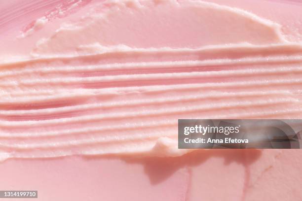 appetizing textured smears of strawberry ice cream. pastel pink background. flat lay style - aardbeienijs stockfoto's en -beelden