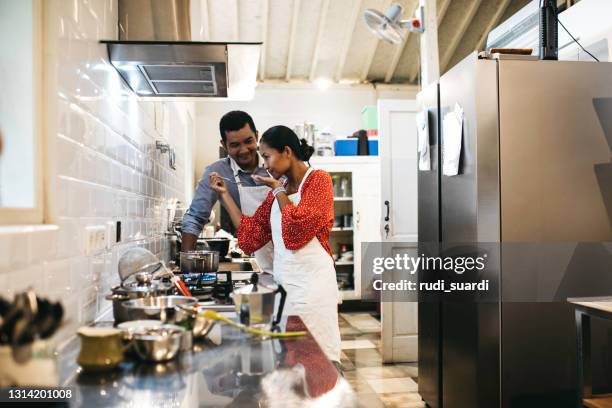 abgeschnittene aufnahme eines jungen ehepaares verkostung der lebensmittel, die sie in der küche zu hause machen - dunstabzugshaube stock-fotos und bilder