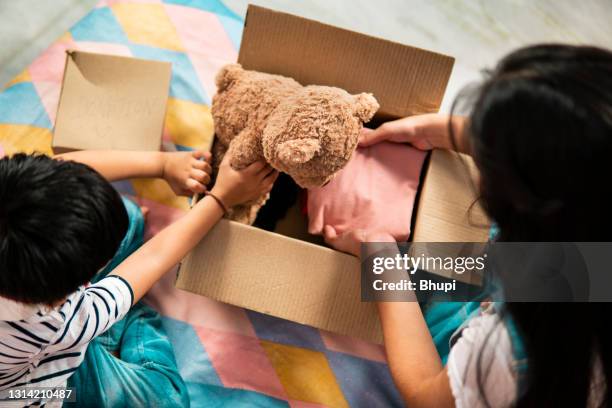 bruder und schwester packen kleidung und spielzeug in die spendenbox. - childrens toys stock-fotos und bilder