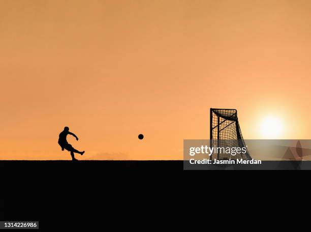 playing football soccer at sunset - football player silhouette stock pictures, royalty-free photos & images