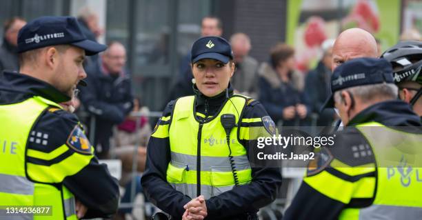 female dutch police officer talking over the situation with male colleagues - police hat stock pictures, royalty-free photos & images